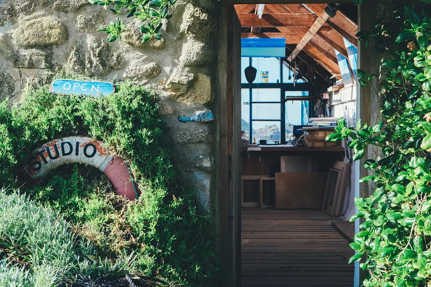 Stone-framed entrance to a small art studio with greenery