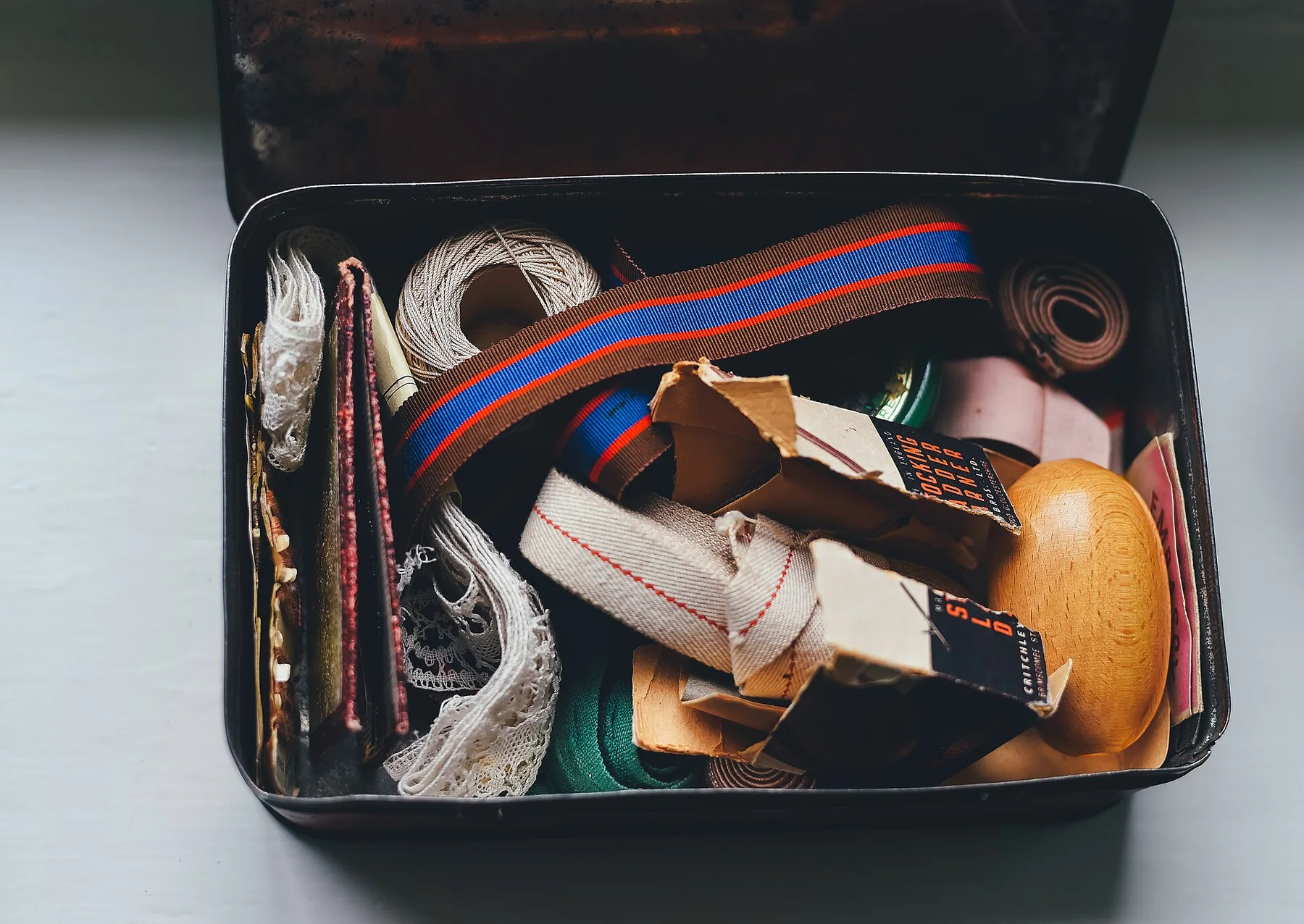An open vintage sewing box holding tools and cloth